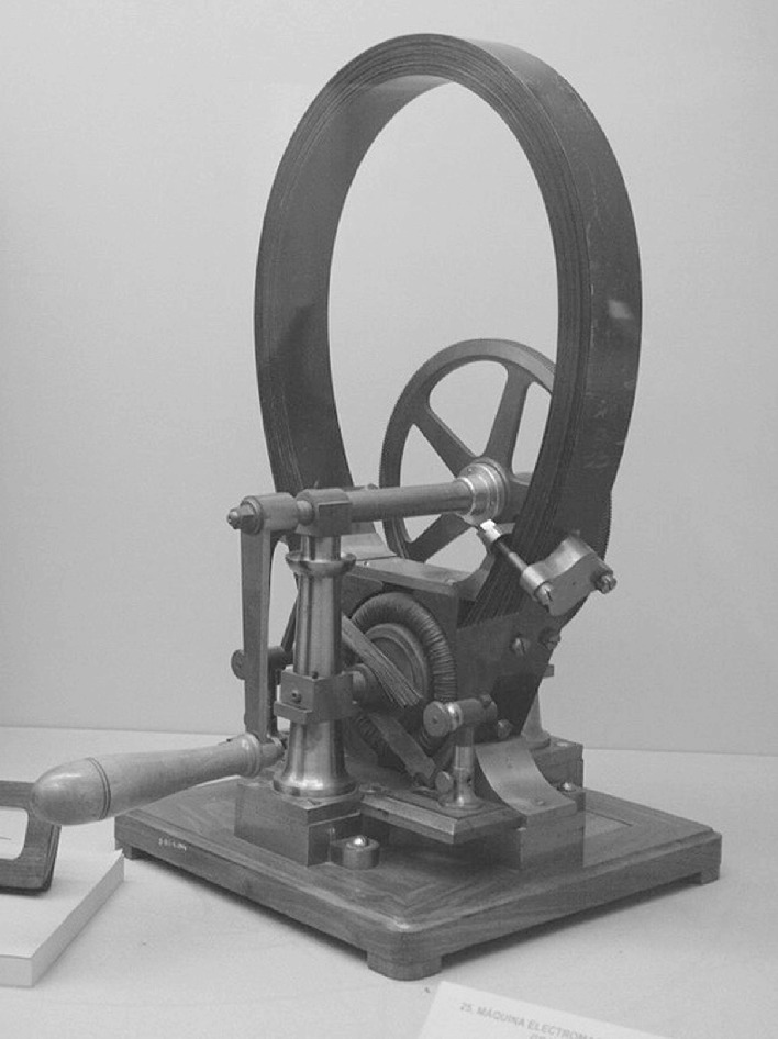 A vintage mechanical device displayed in a museum setting. The apparatus features a large circular component, possibly a flywheel, connected to a smaller gear system. It is mounted on a sturdy base with visible metal rods and levers. The background is plain, emphasizing the intricate design and engineering of the machine.